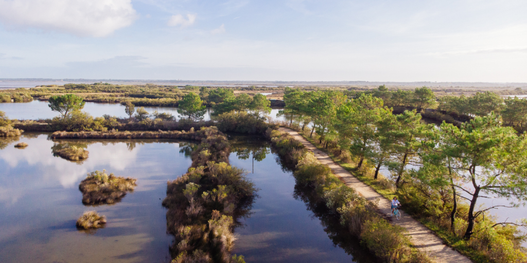 Vue drone du sentier du littoral au Teich, sur laquelle on aperçoit au premier plan une jeune femme à vélo